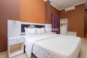a bedroom with a white bed and orange walls at Star Hotel Jaksa Mitra RedDoorz in Jakarta