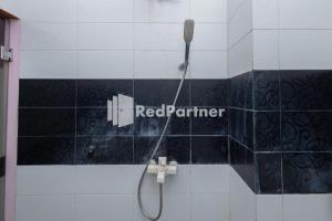 a bathroom with a shower with a red partner sign on the wall at Star Hotel Jaksa Mitra RedDoorz in Jakarta +45 photos