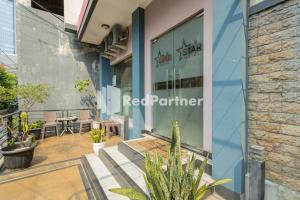a facade of a red perimeter store with tables and chairs at Star Hotel Jaksa Mitra RedDoorz in Jakarta