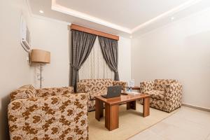 a living room with two chairs and a table with a laptop at فندق غالية احد in Al Madinah