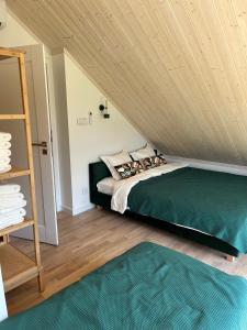 a bedroom with a green bed and a wooden ceiling at Morze Brzoza in Jastrzębia Góra