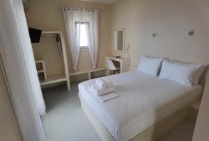 a white bedroom with a white bed and a mirror at Villa Panorama in Irakleia