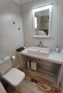 a white bathroom with a toilet and a sink at Villa Panorama in Iraklia