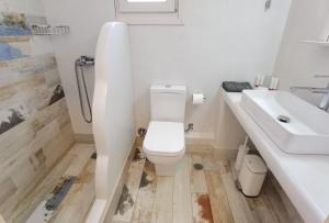 a white bathroom with a toilet and a sink at Villa Panorama in Irakleia