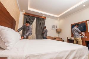three men standing around a bed in a hotel room at فندق غالية احد in Al Madinah