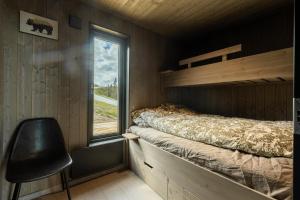 1 dormitorio con cama, ventana y silla en Moderne hytte på Norefjell en Noresund