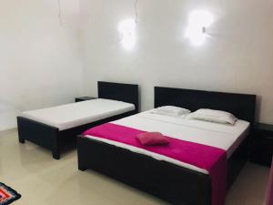 two twin beds in a room with a red blanket at Hambantota Rest House in Hambantota