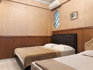 um quarto com duas camas e um ar condicionado na parede em Orange Home Syariah em Bandung