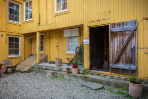 a yellow house with an open door and a porch at Houmbgaarden in Røros