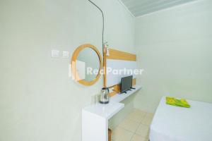Habitación blanca con espejo y mesa blanca en Atiq Homestay Syariah Mitra RedDoorz, en Serang
