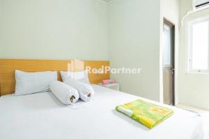 Una cama blanca con dos almohadas y un libro. en Atiq Homestay Syariah Mitra RedDoorz, en Serang