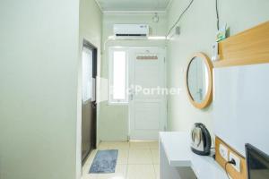 a bathroom with a sink and a mirror and a door at Atiq Homestay Syariah Mitra RedDoorz in Serang