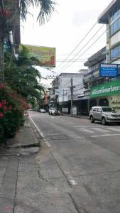 une rue urbaine vide avec des voitures garées sur la route dans l'établissement บ้านโนรีแมนชั่น, à Si Racha