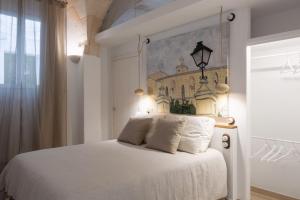 a bedroom with a white bed with a painting on the wall at Hotel Nou Sant Antoni in Ciutadella