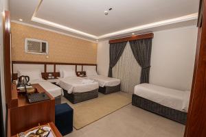 a hotel room with two beds and a desk at فندق غالية احد in Al Madinah
