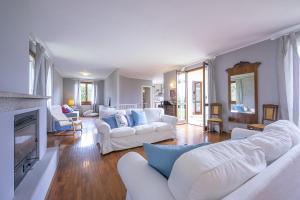 a living room with white furniture and a fireplace at Villa Paola Tremezzo in Tremezzo