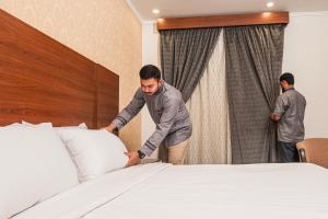 two men are standing next to a bed at فندق غالية احد in Al Madinah