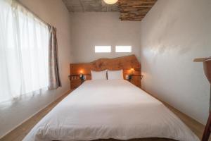 Schlafzimmer mit einem Bett mit weißer Bettwäsche und einem Fenster in der Unterkunft Ichi The Hostel in Minamicho