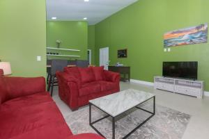 a living room with red furniture and a flat screen tv at Coral Cove at Jardines de Catalina condo in Roatan