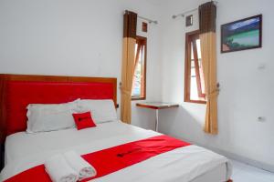 a red and white bed in a room with windows at RedDoorz near Alun Alun Wonosobo 2 in Wonosobo