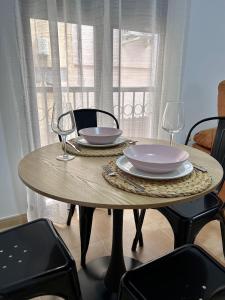 una mesa de madera con dos platos y copas de vino. en Apartamentos la Catedral de Jaén en Jaén