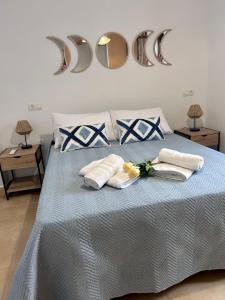 1 cama azul con 2 toallas blancas y 2 espejos en Apartamentos la Catedral de Jaén en Jaén