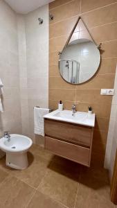 y baño con lavabo, espejo y aseo. en Apartamentos la Catedral de Jaén en Jaén