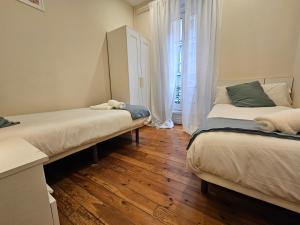 - 2 lits dans une chambre dotée de parquet et de rideaux dans l'établissement 135B2 Precioso Apartamento en Playa San Lorenzo, à Gijón