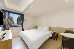 a large white bed in a room with a window at Bonatree Hotel in Busan