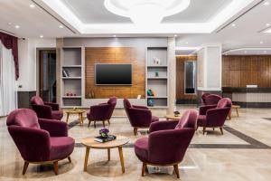 een wachtkamer met paarse stoelen en een flatscreen-tv bij Carina Gold Hotel in Istanbul
