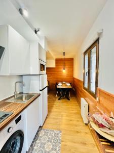 a kitchen with white cabinets and a sink and a table at Nuevo Cosy Loft 4pax Estavar in Estavar