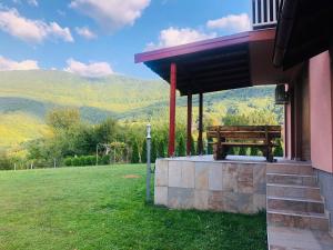 un banco en el porche de una casa con montañas al fondo en Villa Usivak for green quiet holiday near Sarajevo, en Sarajevo