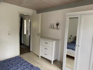 een slaapkamer met een bed, een dressoir en een spiegel bij "Engelsby-Dorf" in Flensburg