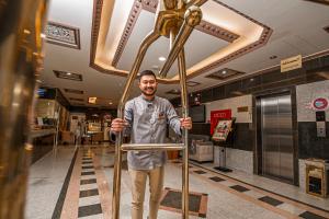 a man standing in a lobby holding a pole at Ghalyt Ohud in Medina