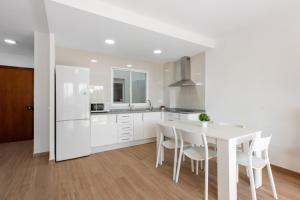 a white kitchen with a white table and chairs at Casa Mar de frente in Málaga +18 photos