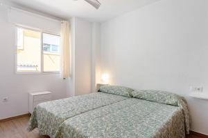 a white bedroom with a bed and a window at Casa Mar de frente in Málaga