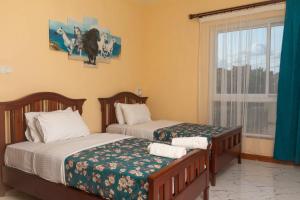 1 dormitorio con 2 camas y ventana en Lux Suites Le Royal Apartments Nyali en Mombasa