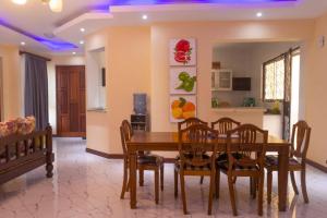 comedor con mesa de madera y sillas en Lux Suites Le Royal Apartments Nyali en Mombasa