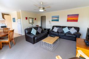 a living room with a black leather couch and a table at Beachfront Apartments in Merimbula