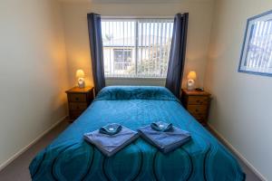 a bedroom with a bed with two towels on it at Beachfront Apartments in Merimbula