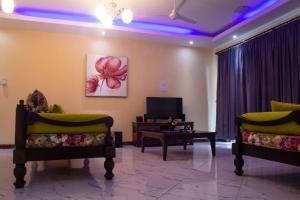 a living room with two chairs and a tv at Lux Suites Le Royal Apartments Nyali in Mombasa