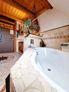 una grande vasca bianca in una stanza con soffitto in legno di Wood & Stone Lodge 2 a Donaueschingen