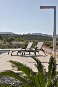 シティアにあるVilla Tropicana, luxury villa with pool by Sternes Propertiesのスイミングプールの隣に座るラウンジチェア2脚