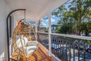 a porch with a swinging chair on a balcony at Poolside Glamour - A Stylish Newcastle Hideaway in Newcastle