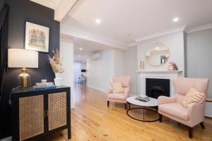 a living room with two chairs and a fireplace at Poolside Glamour - A Stylish Newcastle Hideaway in Newcastle