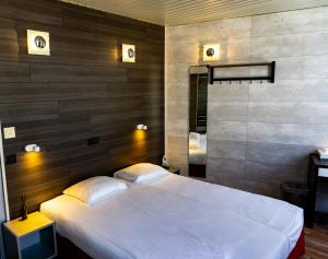 ein Schlafzimmer mit einem weißen Bett und einer Holzwand in der Unterkunft Hotel Richmond in Blankenberge