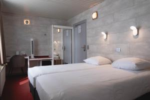 a bedroom with a large white bed and a desk at Hotel Richmond in Blankenberge