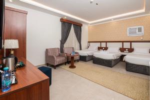 a hotel room with two beds and a desk at فندق غالية احد in Al Madinah +37 photos