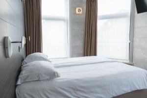 Schlafzimmer mit einem weißen Bett und einem Fenster in der Unterkunft Hotel Richmond in Blankenberge