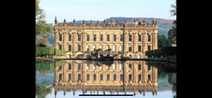 a large building with its reflection in the water at Chatsworth stables in Newbold